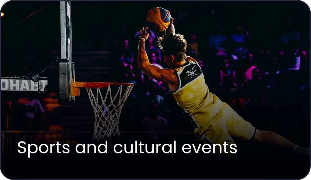 Professional basketball player performing a slam dunk in a brightly lit indoor sports arena in the Middle East